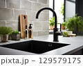 Kitchen island sink with black faucet. This scene is set in a stylish home 129579175