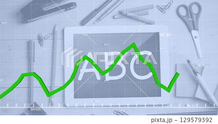Image of green graph over digital tablet screen with abc text and stationery on table 129579392