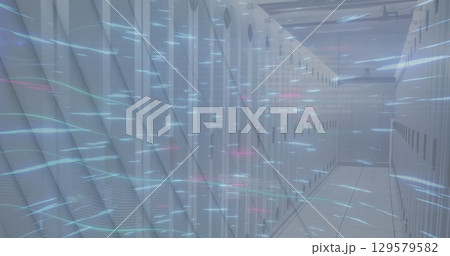 Image of glowing blue light trails spinning over empty computer server room 129579582