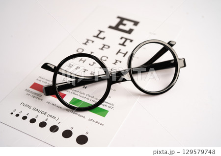 Glasses on eye testing exam chart to check eyesight accuracy of reading. 129579748