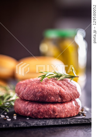 Raw burger beef patties on cutting board on black table. 129580052