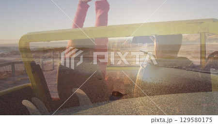 Image of light over happy caucasian couple in car on beach 129580175