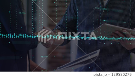 Shaking hands, business professionals in modern office holding clipboard, tablet and documents Shaking hands, business professionals in modern office holding clipboard, tablet and documents 129580279