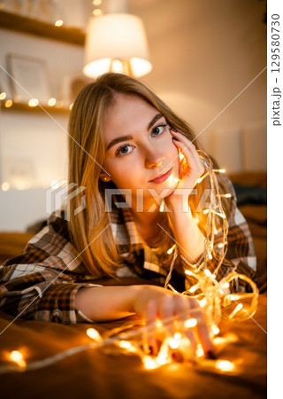 Woman Relaxing with String Lights in Cozy Atmosphere Woman Relaxing with String Lights in Cozy Atmosphere 129580730