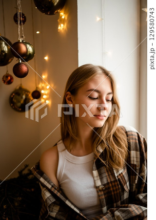 Young Woman Relaxing by Window During Festive Season 129580743