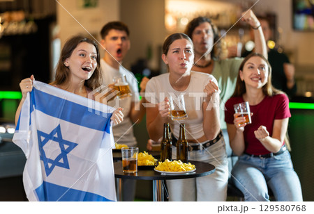 Group of friends cheer together for their favorite Israeli team in beer bar Group of friends cheer together for their favorite Israeli team in beer bar 129580768