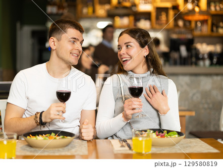 Couple sitting in a restaurant, chatting and drinking wine 129580819