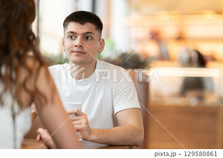 Guy in cafe sits opposite female companion, has nice conversation Guy in cafe sits opposite female companion, has nice conversation 129580861