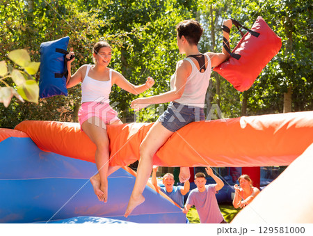 Women having pillow fight between each other in outdoor amusement park 129581000
