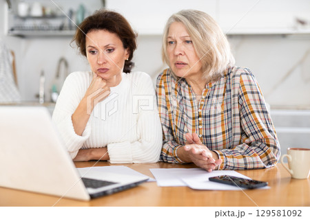 Old and middle-aged women speaking sadly by video-call using laptop 129581092
