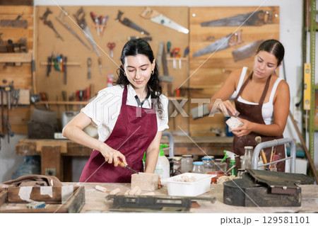 Girl working with wood in carpentry workshop 129581101