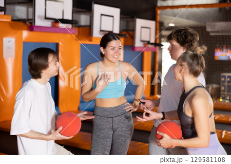Two women and two teenager guys communicate in trampoline center 129581108