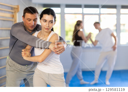 Woman practices blows to the head of a male attacker during self defense training 129581119