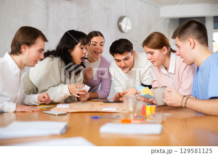 Happy students playing board game at table in campus 129581125