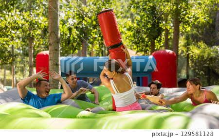 Girl guarding toy chickens fighting off friends with inflatable log 129581128
