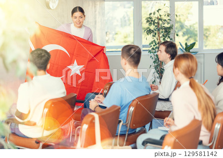 Young female professor showing turkish flag to group of students Young female professor showing turkish flag to group of students 129581142