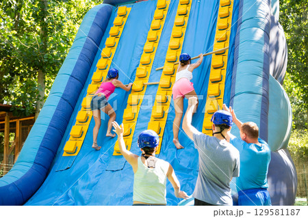 Women climbing up on slide in adventure park 129581187