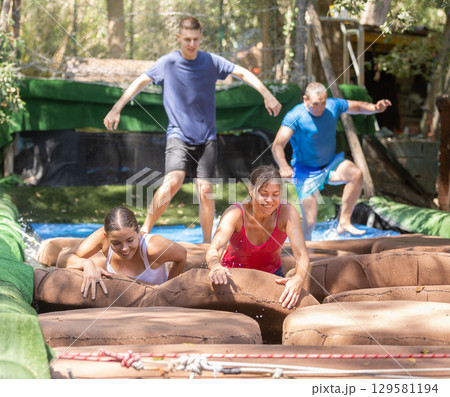 Men and women reaching finish of water obstacle course 129581194