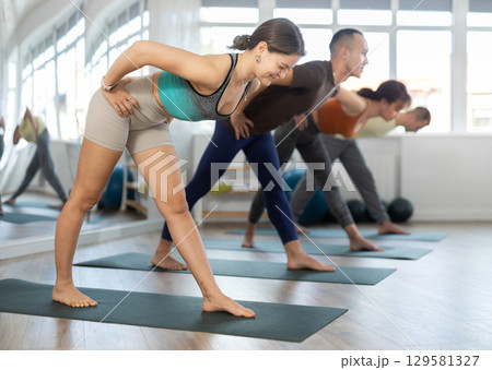 Portrait of young active sporty people practicing yoga with group at fitness center Portrait of young active sporty people practicing yoga with group at fitness center 129581327