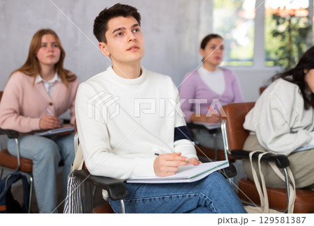 High school students sit at their desks and listen carefully to the teacher at lesson at school High school students sit at their desks and listen carefully to the teacher at lesson at school 129581387