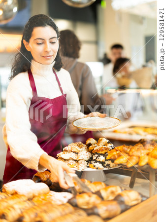 Woman folding fresh pastries Woman folding fresh pastries 129581471