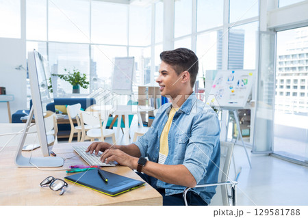 Mid adult man wearing denim shirt using computer and drawing tablet at open-plan office, copy space Mid adult man wearing denim shirt using computer and drawing tablet at open-plan office, copy space 129581788