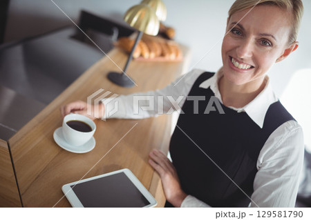 Woman in business outfit sitting at cafe counter holding coffee cup and using tablet, copy space Woman in business outfit sitting at cafe counter holding coffee cup and using tablet, copy space 129581790