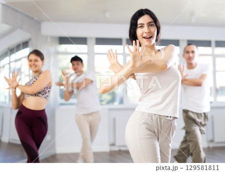 Group of people, girls and guys in sportive casual style clothes dancing in choreography class 129581811