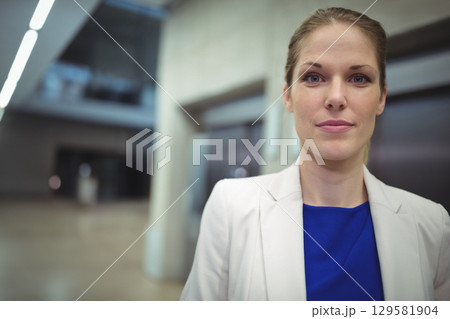 Professional woman standing in office lobby by elevator doors under linear lighting, copy space Professional woman standing in office lobby by elevator doors under linear lighting, copy space 129581904