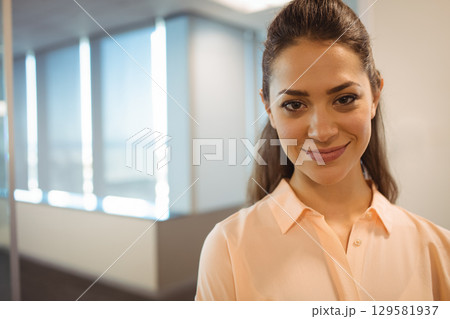 Woman standing in modern office corridor by tall windows with vertical blinds, copy space Woman standing in modern office corridor by tall windows with vertical blinds, copy space 129581937