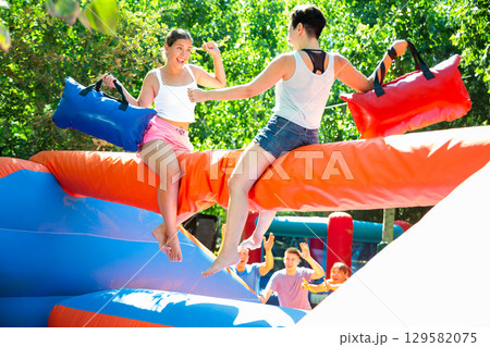 Women having pillow fight between each other in outdoor amusement park 129582075