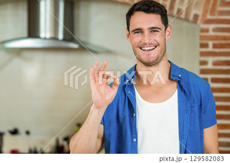Man standing in kitchen making OK gesture under steel hood by brick arch, copy space 129582083