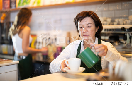 Mature female barista making coffee 129582187