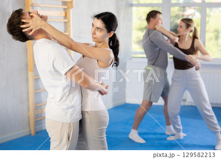 Young woman and guy training self-defense techniques Young woman and guy training self-defense techniques 129582213