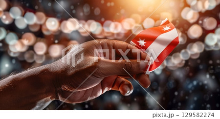 Hand holding small georgian flag with festive bokeh background Hand holding small georgian flag with festive bokeh background 129582274