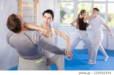 Young woman and adult man training self-defense techniques Young woman and adult man training self-defense techniques 129582354