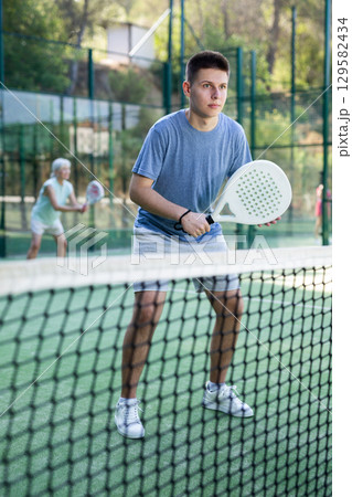 Man training to play tennis on padel court outdoor 129582434