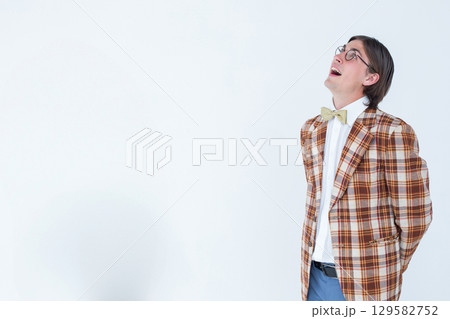 Man standing clasping hands behind back in studio wearing blazer and bow tie, copy space Man standing clasping hands behind back in studio wearing blazer and bow tie, copy space 129582752