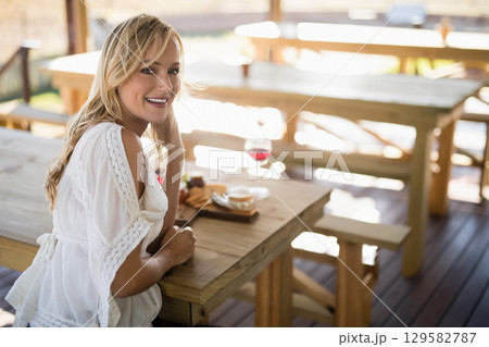Woman sitting at table on terrace sipping red wine with cheese board and fruit, copy space Woman sitting at table on terrace sipping red wine with cheese board and fruit, copy space 129582787