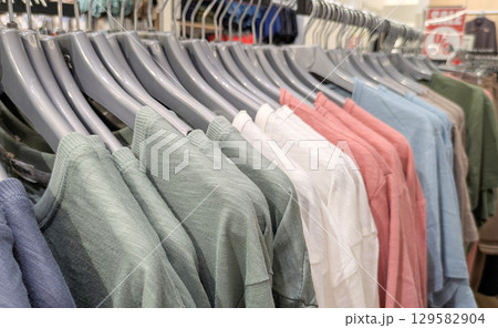 Clothes rack in the store displays various cotton T-shirts in different colors. Ideal for summer fashion, retail and shopping concepts 129582904