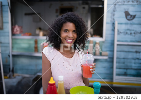 African American woman sitting at teal food truck holding cup with striped straw and condiments African American woman sitting at teal food truck holding cup with striped straw and condiments 129582918
