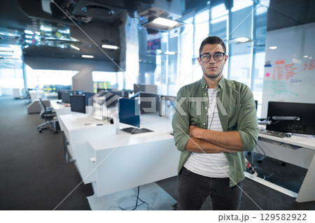 Male office worker standing near whiteboard and desks with monitors at open office, copy space Male office worker standing near whiteboard and desks with monitors at open office, copy space 129582922