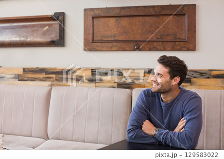 Man sitting at dark wood table wearing navy shirt and wristwatch in dining booth, copy space Man sitting at dark wood table wearing navy shirt and wristwatch in dining booth, copy space 129583022