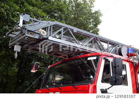 Front of firefighting vehicle with long ladder to rescue people from height. Main rescue vehicle with folding ladder to access the fire. Firefighting vehicle concept with special equipment Front of firefighting vehicle with long ladder to rescue people from height. Main rescue vehicle with folding ladder to access the fire. Firefighting vehicle concept with special equipment 129583107