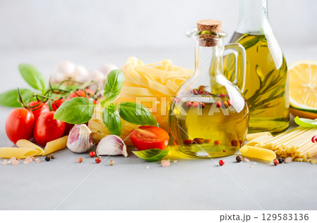 Fresh Italian food ingredients including olive oil, tomatoes, garlic, and pasta arranged beautifully on a light background for culinary inspiration Fresh Italian food ingredients including olive oil, tomatoes, garlic, and pasta arranged beautifully on a light background for culinary inspiration 129583136