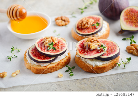 Delicious fig and walnut toast topped with creamy cheese, drizzled with honey, showcasing a gourmet breakfast or snack idea with fresh ingredients 129583147