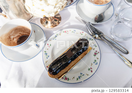 French eclair on a plate on a table in a restaurant in Paris, France French eclair on a plate on a table in a restaurant in Paris, France 129583314