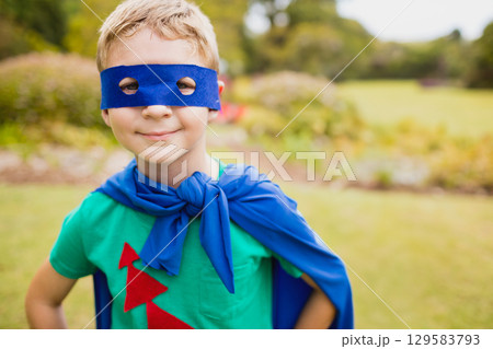 Boy posing with hands on hips in garden wearing blue felt mask and matching cape Boy posing with hands on hips in garden wearing blue felt mask and matching cape 129583793