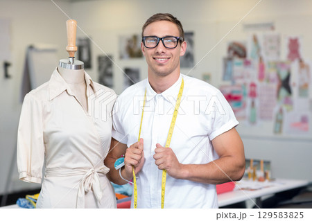 Male designer standing in design studio using measuring tape near wrap dress form, copy space Male designer standing in design studio using measuring tape near wrap dress form, copy space 129583825