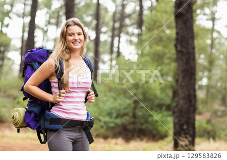 Woman standing on forest trail wearing striped tank top and carrying hiking backpack, copy space Woman standing on forest trail wearing striped tank top and carrying hiking backpack, copy space 129583826